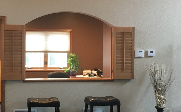 Interior shutters framing out a cutout between the kitchen and living room